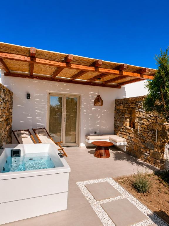 a patio with a hot tub and a stone wall at Anastasia's Luxury Suite with jacuzzi in Angairiá