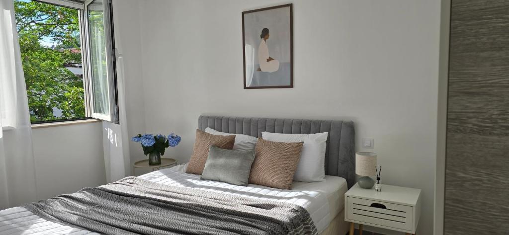 a white bedroom with a bed with pillows and a window at Kamelija LUX in Đenovići