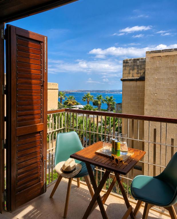 a balcony with a wooden table and two chairs at Harba - An Escape at Fort Chambray in Għajnsielem