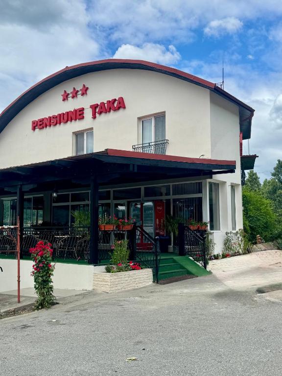 a restaurant with a sign on the side of a building at Pensiunea Taka in Orşova