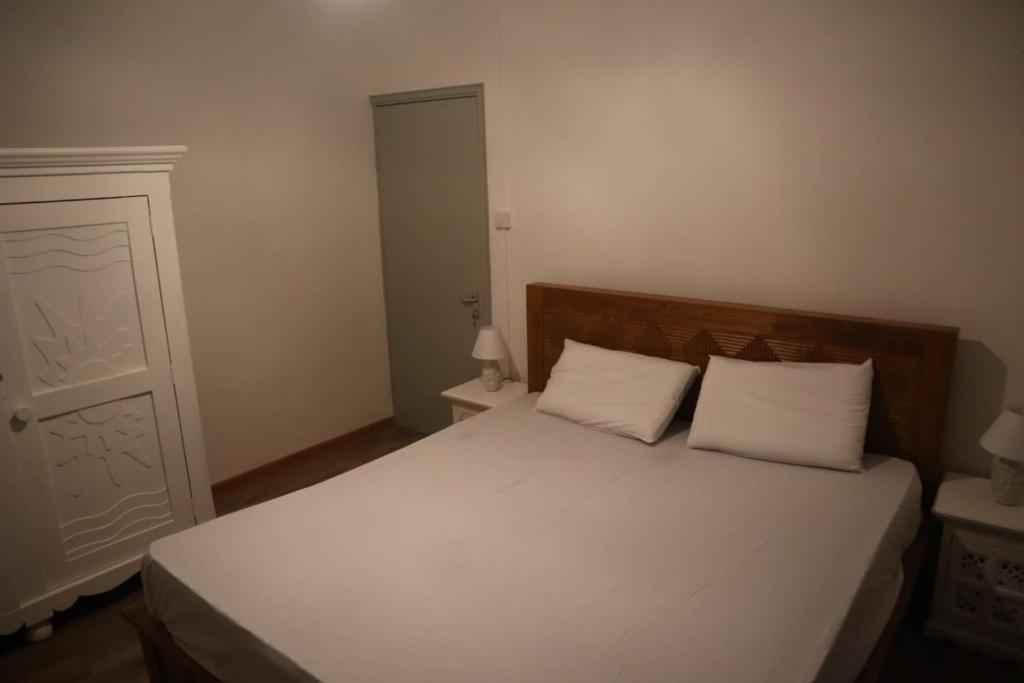 a bedroom with a white bed with two white pillows at Maison des Anges in Mahébourg
