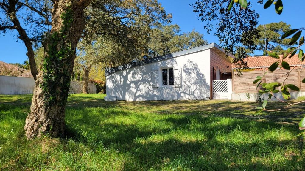 a small white building in a yard with a tree at Proche de la plage, très bien situé in Ondres