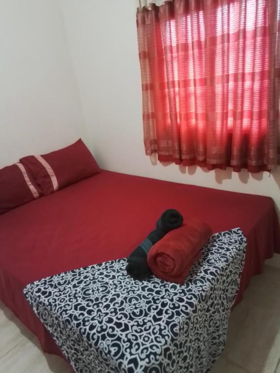 a bedroom with a bed with red sheets and a red blanket at psalms in Cunupia Village
