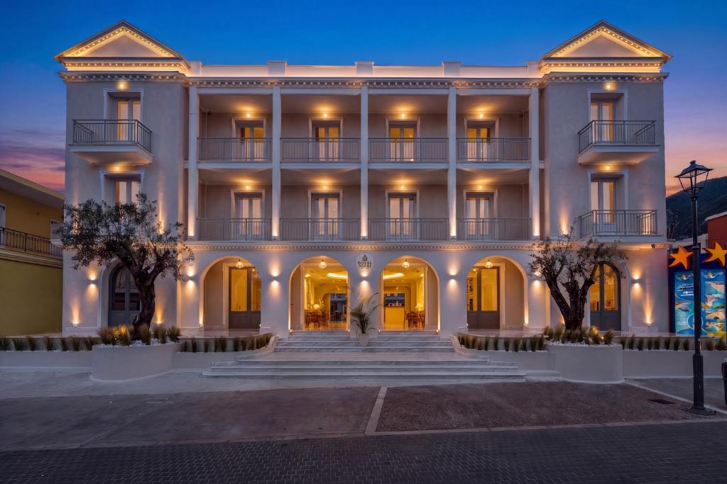 a large white building with trees in front of it at Royal Nidri Suites in Nydri