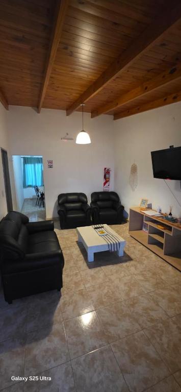 a living room with black couches and a tv at Alojamiento Dina in Puerto Madryn