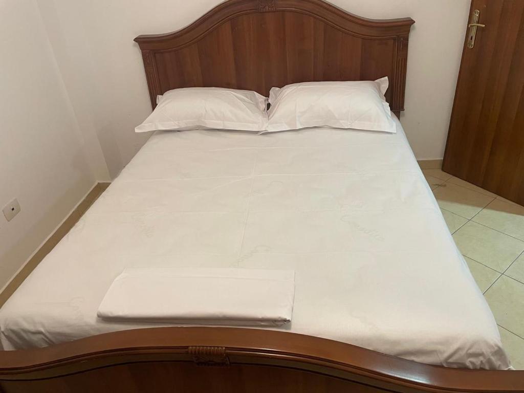 a bed with white sheets and pillows in a room at Olive in Tirana
