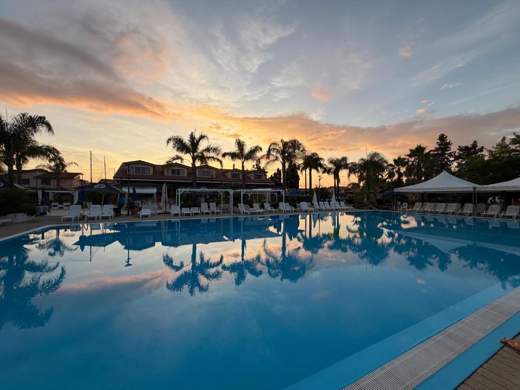 a large swimming pool with a sunset in the background at Kavani in Pizzo