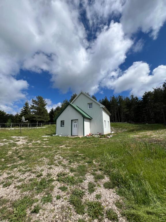 a white house in a field with a cloudy sky at Everpine house in Žabljak