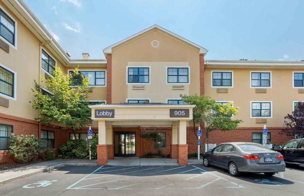a building with a car parked in a parking lot at Extended Stay America Suites - Long Island - Bethpage in Bethpage