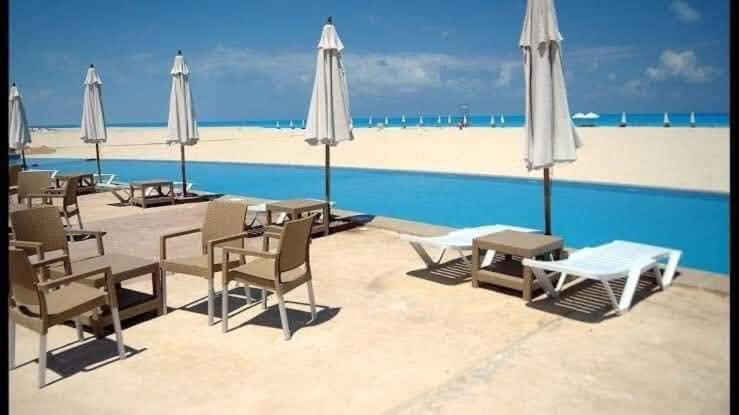 a group of chairs and umbrellas next to a pool at Chalet with roof pool view in Dawwār ‘Abd Allāh