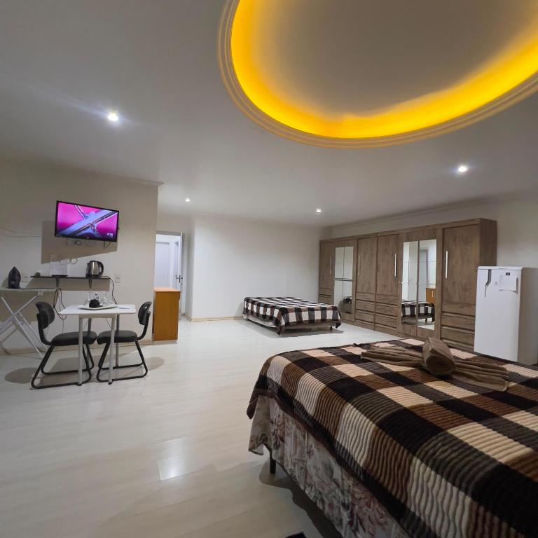 a room with a bed and a desk and a tv at Quarto Suíte Master Luxo in Santana do Livramento