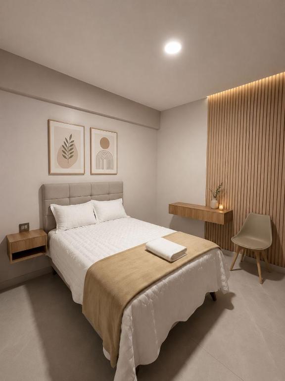 a bedroom with a large bed and a chair at Centrica Suite Hotel in Huarmey