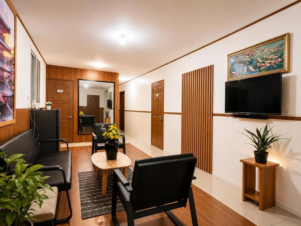 a living room with chairs and a tv on a wall at Axis Pension Hotel in Mactan