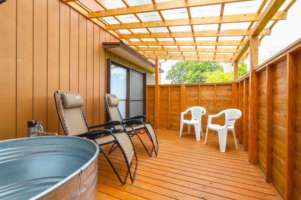 a deck with chairs and tables and a pergola at サウナ&ステイ吉日荘-益子町のプライベートサウナ付の貸切古民家 BBQ 高速Wi-fi in Mashiko