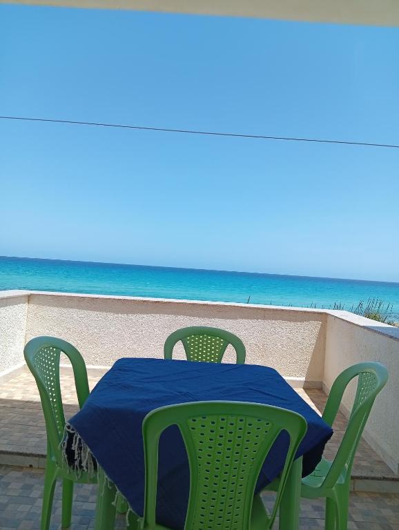 a table and chairs with the beach in the background at Résidence R in Salakta