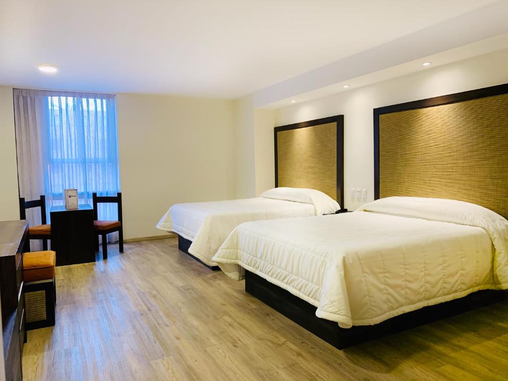 a hotel room with two beds and a table at Hotel Lepanto Reforma in Mexico City