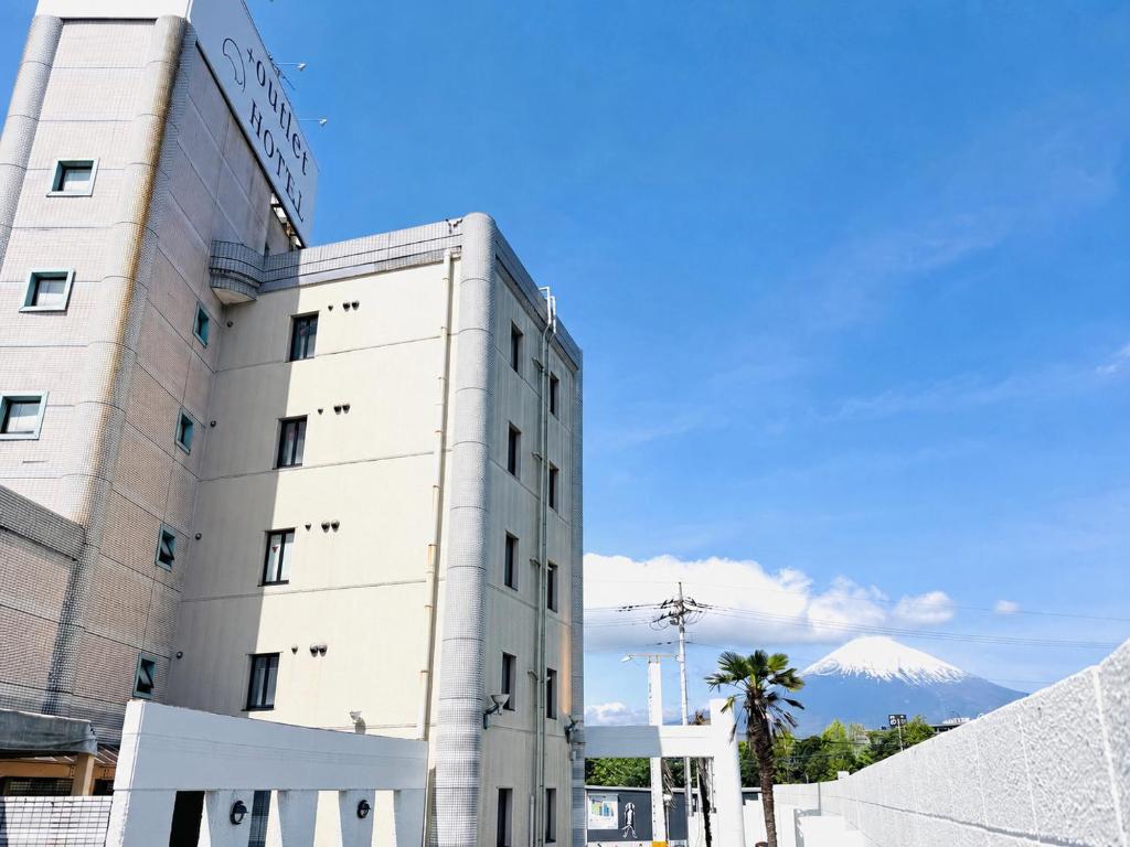 a white building with a mountain in the background at 富士OUTLET Hotel in Gotemba