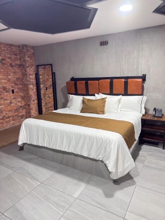 a bedroom with a large bed and a brick wall at Hotel Van Gogh Aeropuerto Gdl in Guadalajara