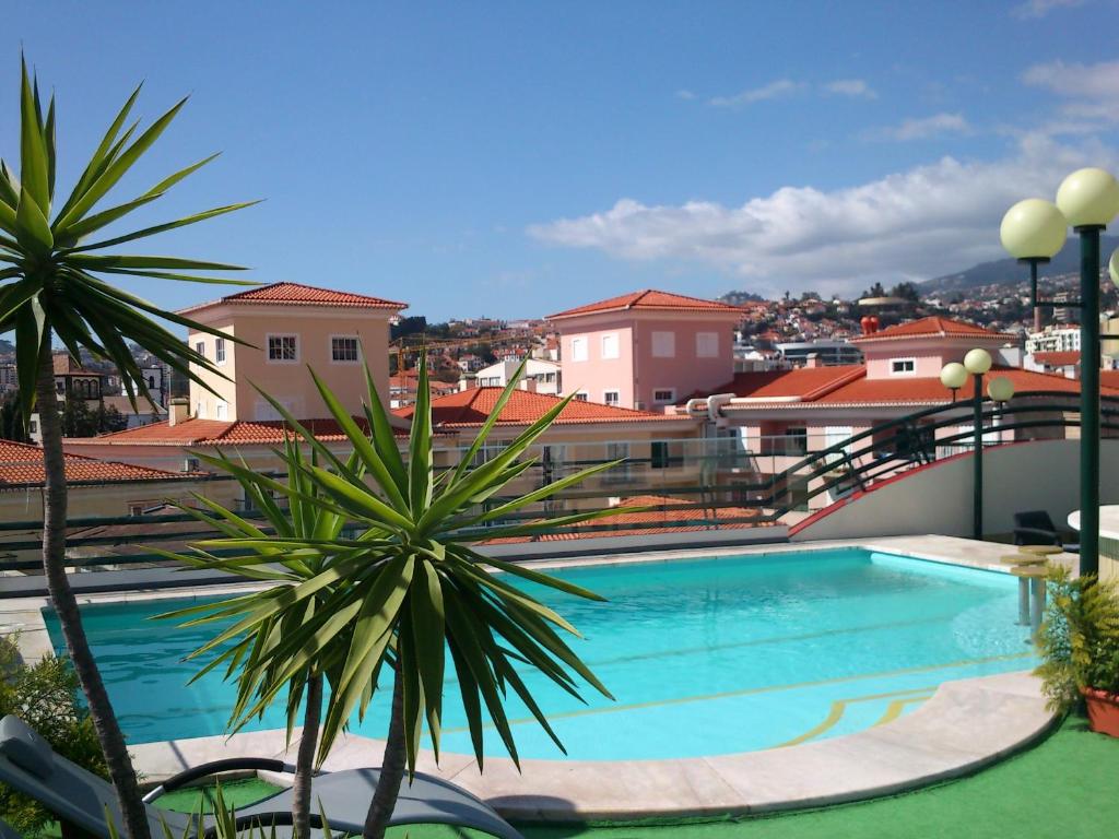 a swimming pool on top of a building with palm trees at Hotel Windsor in Funchal