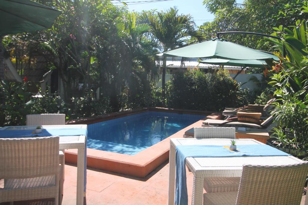 a swimming pool with a table and an umbrella at New Balengku Dua Hotel - Adults Only in Gili Islands