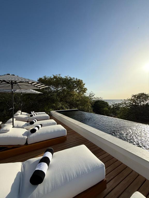 a row of chaise lounges on a deck near a swimming pool at NOAM by the sea in Tamarindo