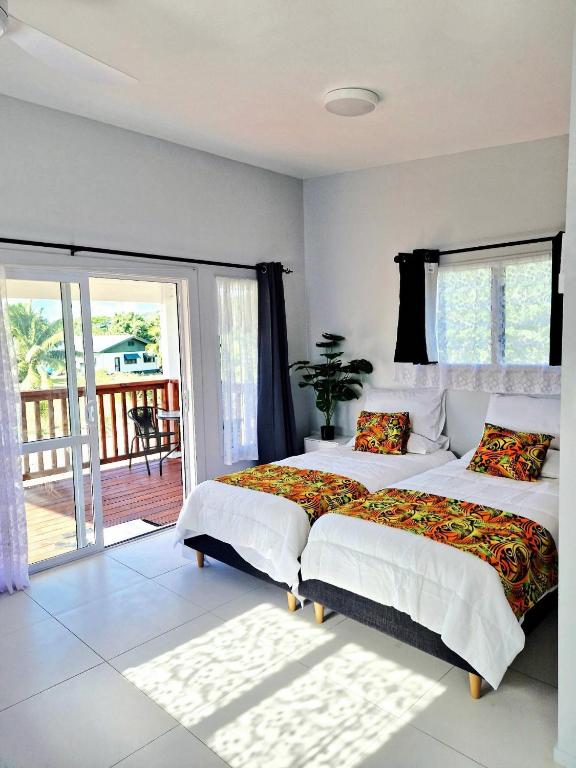 a bedroom with two beds and a balcony at Mama's Mountain Views in Avarua