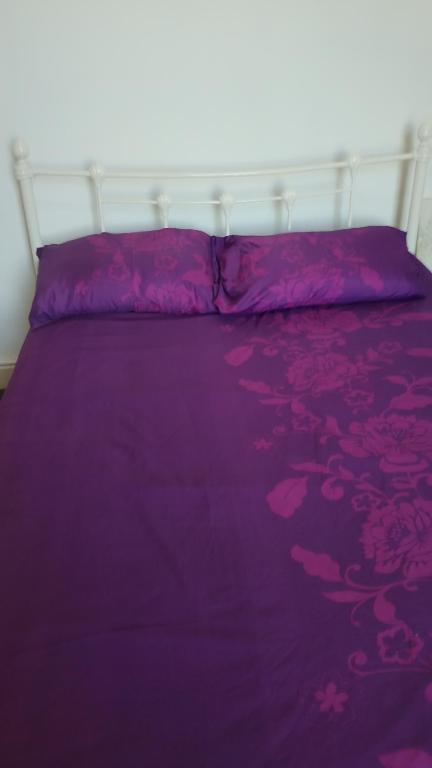 a purple bed with a white headboard and purple sheets at AAA lodge in Middlesbrough