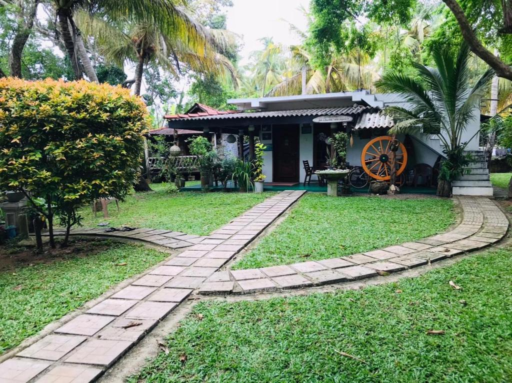 a house with a brick walkway in front of a yard at Yaye Guest House in Tissamaharama