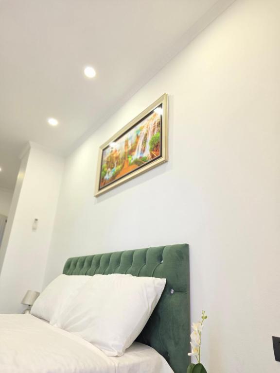 a bedroom with a green headboard and a painting on the wall at Crown Villa in Golem