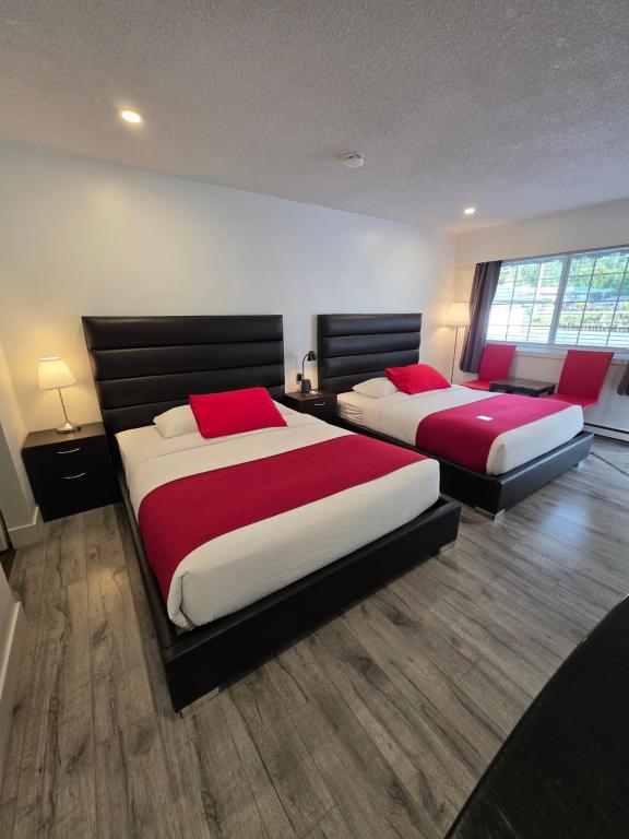 a bedroom with two beds with red and white sheets at Alpine Motel in Hope