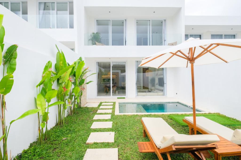 an external view of a house with a swimming pool and an umbrella at Blanca Karma Villas in Uluwatu