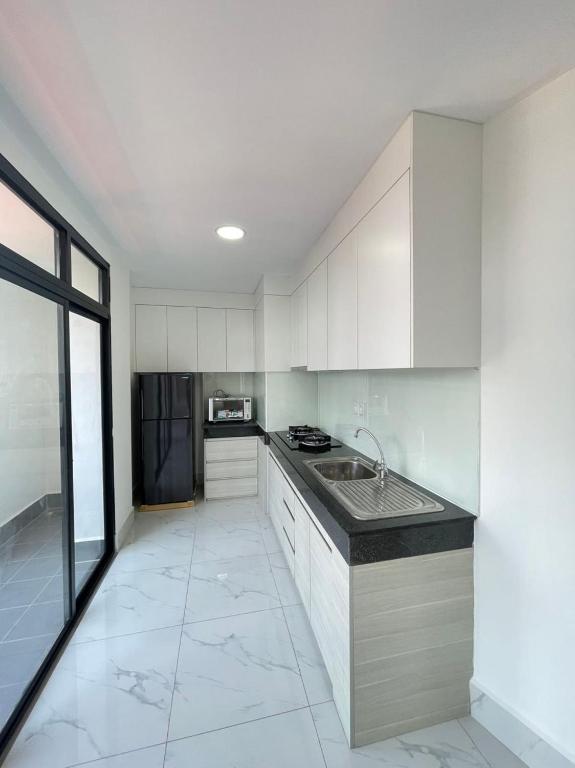 a kitchen with white cabinets and a black refrigerator at Skyline hotel in Phnom Penh