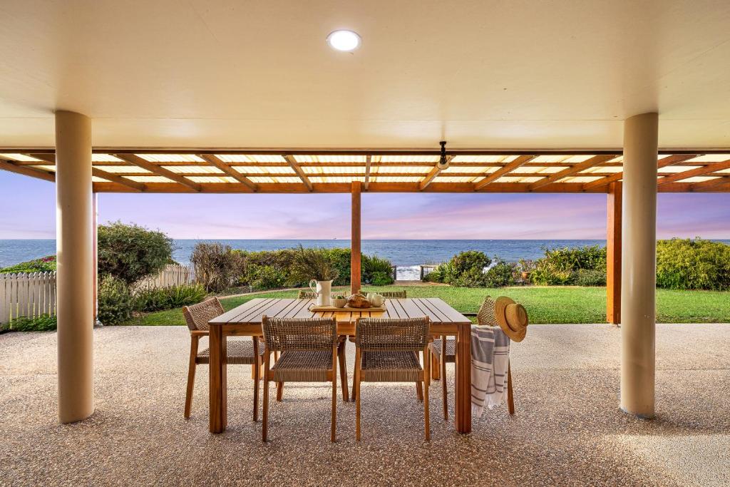 a dining table and chairs under a pergola at Whale Song House in Bargara