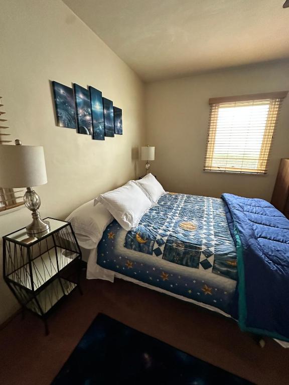 a bedroom with a bed with a blue comforter and a window at Sacred Heart House in Montebello
