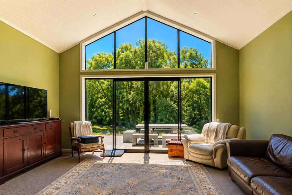 a living room with a couch and a large window at Riverside Retreat in Twizel