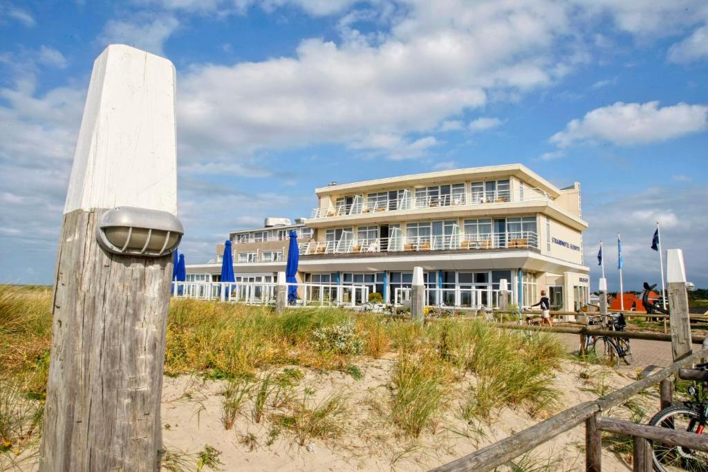 
a large white building with a clock on it at WestCord Strandhotel Seeduyn in Oost-Vlieland
