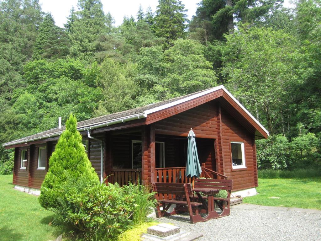 a log cabin with an umbrella in front of it at 18 Lamont Lodges in Dunoon