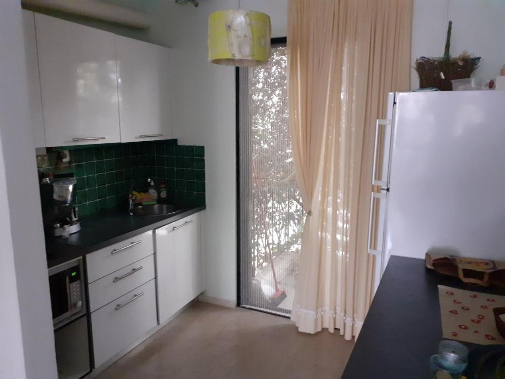 a kitchen with a sink and a refrigerator and a window at Dream house steps from sea in Pídima Kyrás