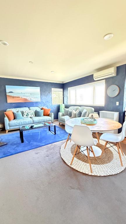 a living room with couches and a table and chairs at Beach Apartment in Papamoa