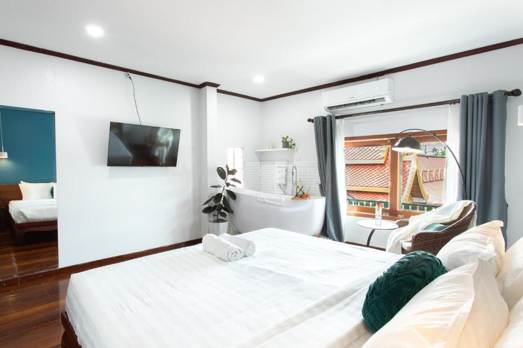 a bedroom with a large white bed and a bathroom at BlueHome Vientiane in Vientiane