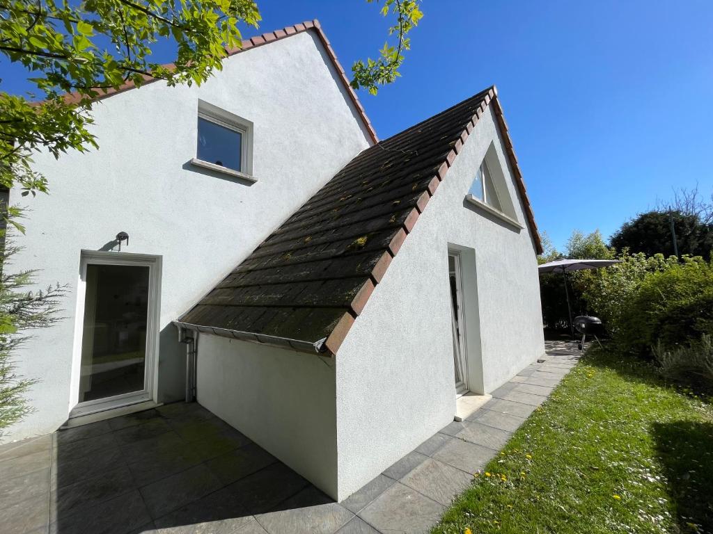 a white house with a black roof at Maisons avec terrasse et parking in Colmar