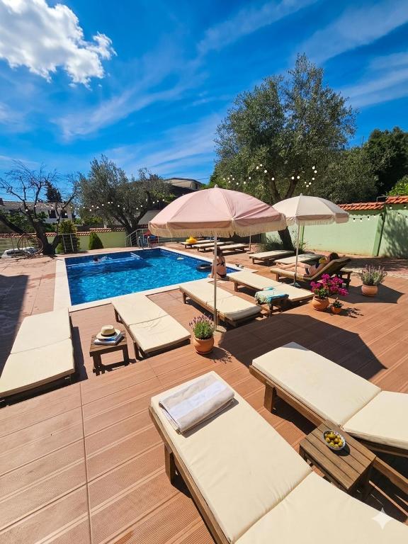 ein Pool mit vielen Liegestühlen und Sonnenschirmen in der Unterkunft Button Aparthotel in Dobra Voda
