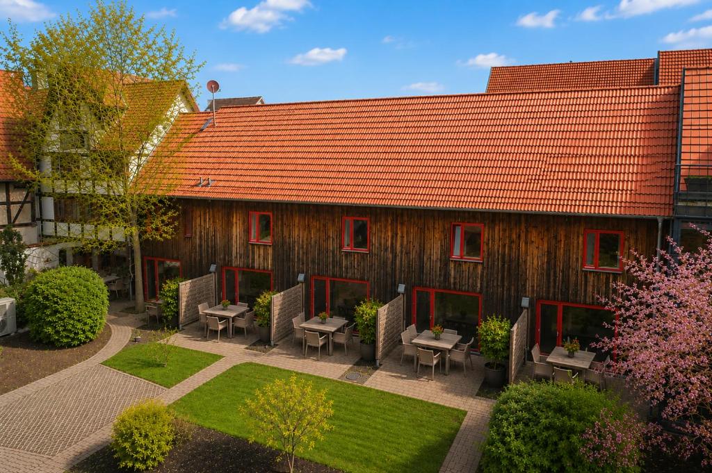 a building with a red roof with chairs and a garden at Elementa City Lodge Quedlinburg 2 in Quedlinburg