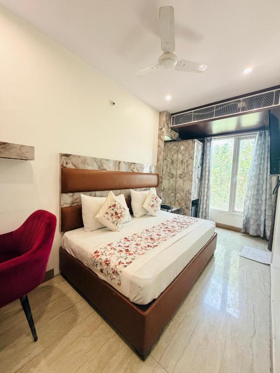 a bedroom with a large bed and a red chair at Hotel Heritage Suites in New Delhi