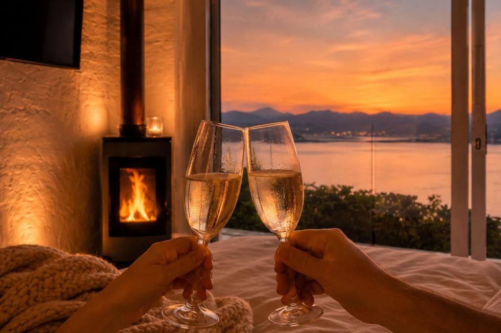 two people holding champagne glasses in front of a fireplace at Romantic Cosy fire-place at Enso Botanico Boutique Villa, Kosmos in Hartbeespoort