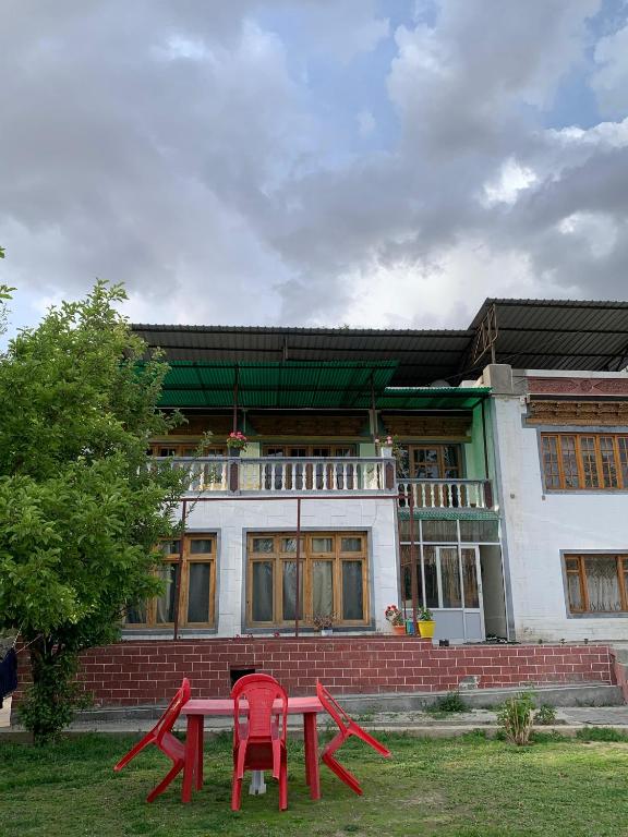 two red picnic tables in front of a building at Larikha stay chumpa in Leh