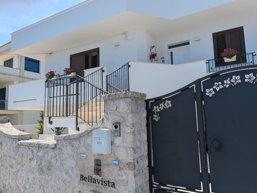 a white house with a black gate and a stone wall at b&b Bellavista in Castro di Lecce