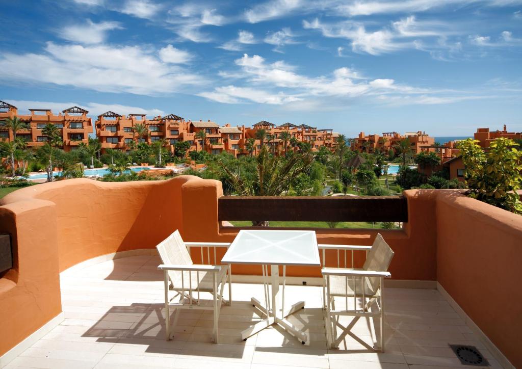 a white table and chairs on a balcony with buildings at Royal Hideaway Sancti Petri in Chiclana de la Frontera