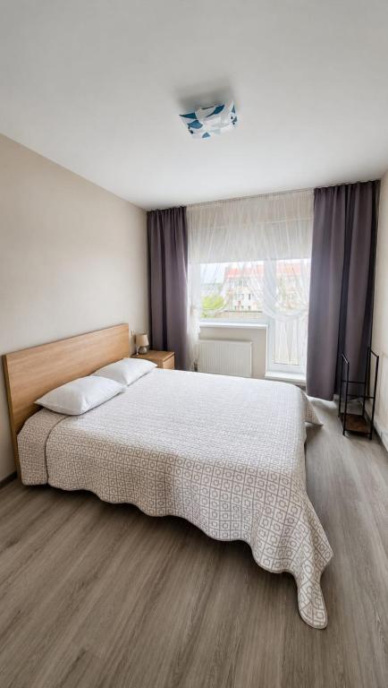 a bedroom with a large bed and a window at Viktorija Apartament in Liepāja