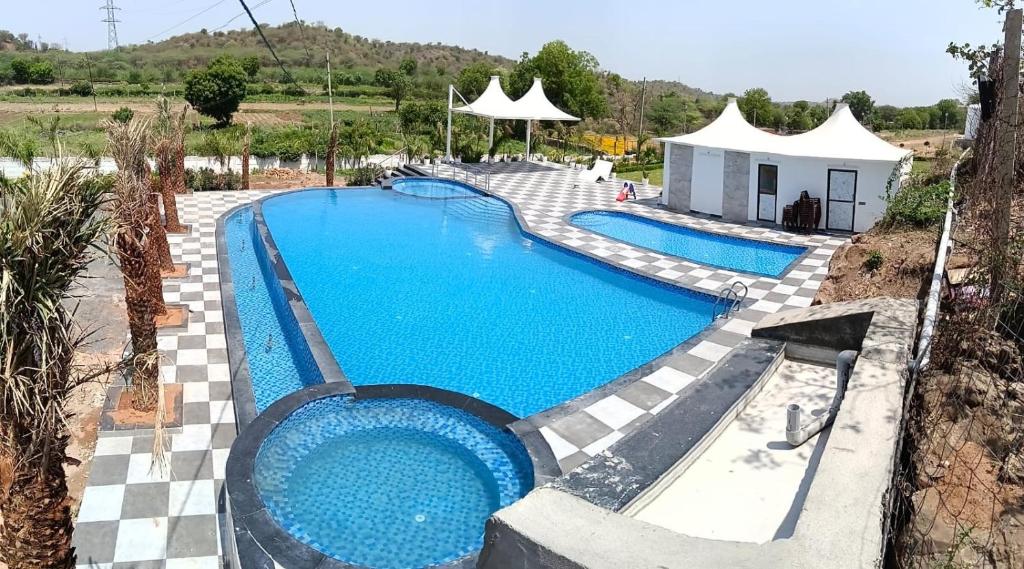 a swimming pool with blue water in a resort at Shubham Resort in Bhilwara
